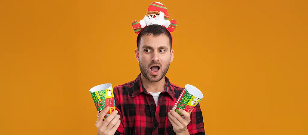 Kar&aacute;csonyi nyerem&eacute;nyeket illusztr&aacute;l&oacute; jelenet, meglepett f&eacute;rfival &eacute;s &uuml;nnepi hangulat&uacute; aj&aacute;nd&eacute;kpoharakkal