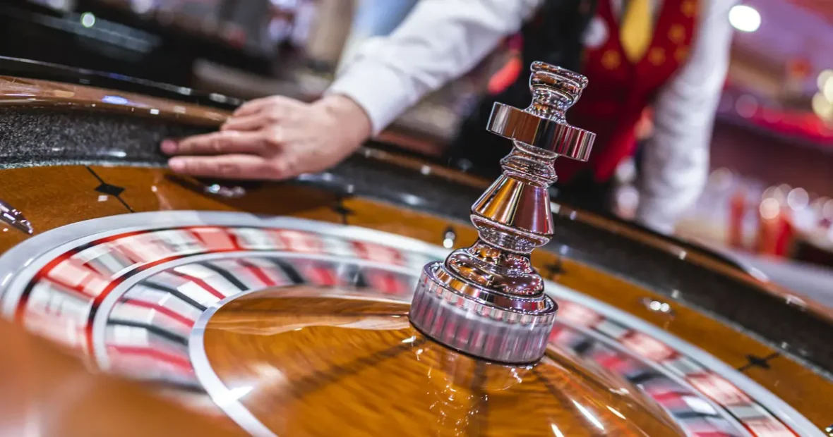 Forgó rulettkerék közelről, a krupié keze a kerék mellett, kaszinó környezetben