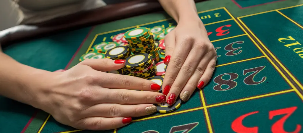 A j&aacute;t&eacute;kos zsetonokat rendez a rulettasztalon, j&oacute;l l&aacute;that&oacute; sz&aacute;mmezőkkel &eacute;s k&uuml;l&ouml;nb&ouml;ző t&eacute;tekkel