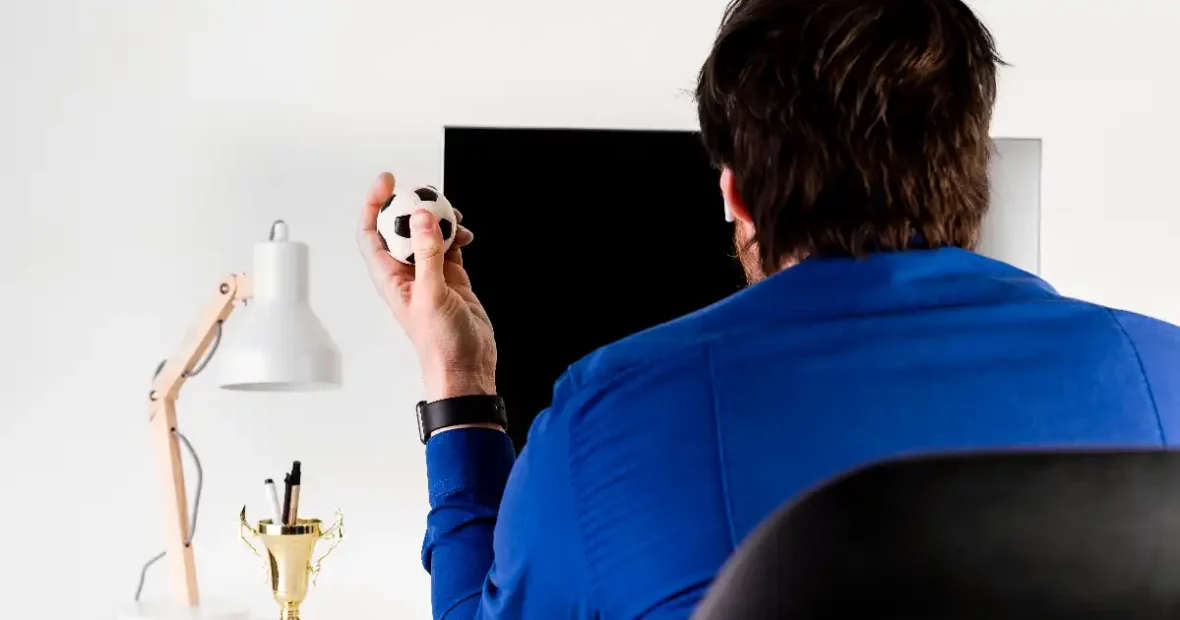 Dán bajnokság elemzése férfi labdát tart kezében számítógép előtt sportfogadás közben