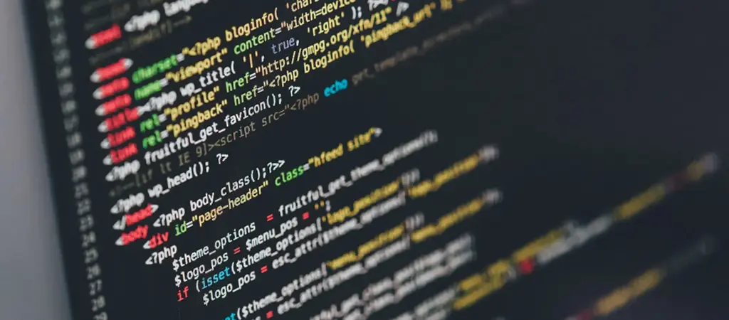 Programk&oacute;d k&ouml;zelről egy s&ouml;t&eacute;t h&aacute;tterű sz&aacute;m&iacute;t&oacute;g&eacute;pes k&eacute;pernyőn